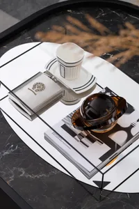 Minimalist coffee table with a white marble surface and various items such as a hip flask, a ceramic cup, a teapot, and a boo
