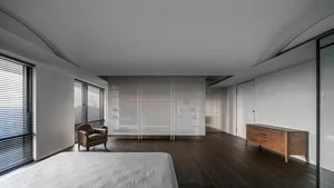Modern bedroom with dark wood flooring, black blinds, and a wooden cabinet.