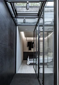 Modern bedroom featuring glass walls and concrete floor.