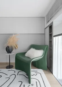 Modern living room featuring a green leather chair with a fluffy white pillow, styled with dried grass flowers in a vase on a