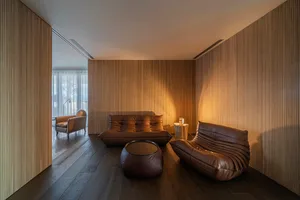 A modern living room featuring wooden paneling and leather furniture.
