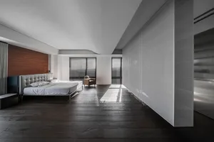 Modern minimalist bedroom featuring a wood-finished bed and glass panels.
