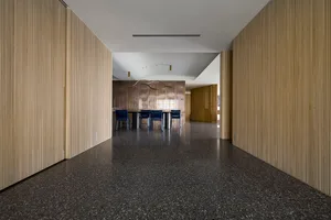 A modern open-plan office with wood paneling on the walls and a black floor.