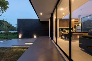 A minimalist residential interior featuring concrete, glass, and wooden walls.