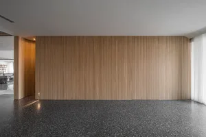 A modern living room with wooden paneled walls and a speckled floor.