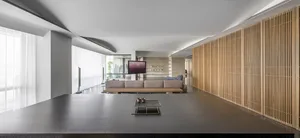 A modern living room with concrete flooring, a wooden panel wall, and soft furnishings.