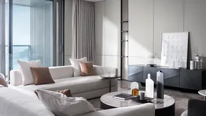 A modern living room featuring white sofas with brown and beige cushions, glass coffee tables, concrete accents, and large wi