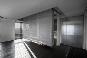 A minimalist closet with glass doors and a white sheer curtain.