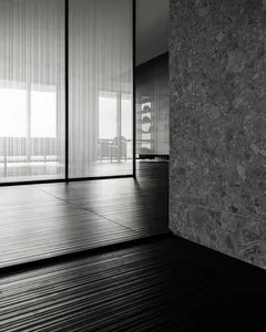 A modern minimalist room with large glass windows and dark flooring.