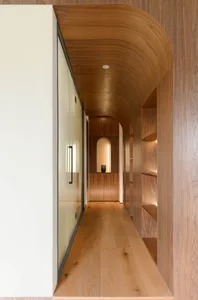 A hallway with a curved wooden wall and built-in shelves.