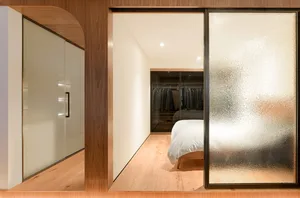 A minimalist bedroom with a bed, closet, and wooden floors.