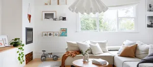 A minimalist living room with a fabric couch, wooden floor, and decorative elements.