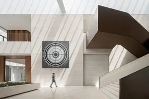 A minimalist office lobby with a concrete wall featuring a circular geometric pattern.