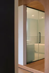 Modern bathroom with glass door and minimalist design.