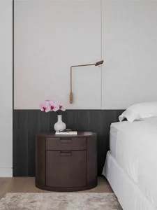 Modern bedroom featuring a wooden nightstand with a vase of flowers and a lamp.