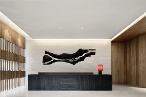 A modern entry way featuring a black wooden desk, a red lamp, and a large abstract black and white sculpture on a white and b