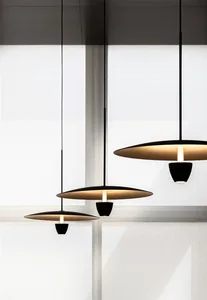Three minimalist black pendant lights hanging from the ceiling, emitting warm light.