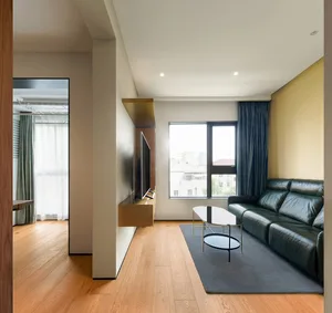 Modern living room featuring a black leather sofa and a glass coffee table on a wooden floor.