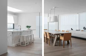 Modern kitchen and dining area with marble countertops and wooden flooring.