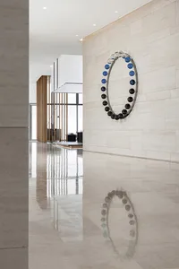A modern lobby featuring a glass circle sculpture on a beige tiled wall.
