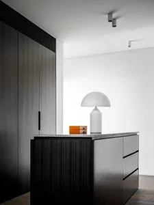 A modern interior design featuring a sideboard made of blonde wood with a minimalist lamp on top, creating an elegant and sop