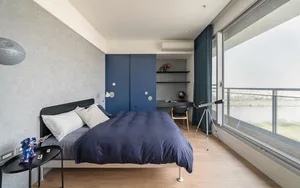 Modern bedroom featuring blue ecliptic, wooden floor, and glass window overlooking a scenic view.