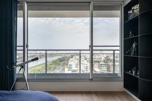 Modern bedroom featuring a glass telescope and a view of a cityscape