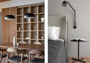 A minimalist bedroom featuring a textured grey wall, white bed with a grey comforter, and a black adjustable lamp on a small 