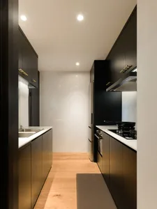 Modern kitchen featuring black cabinets, marble countertops, and metallic finishes.