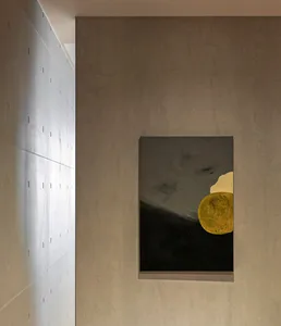 A piece of abstract art featuring a golden circle on a black and gray textured concrete wall.