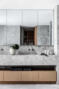 Modern bathroom featuring marble tiles and countertops, with a wooden vanity and minimalist design.