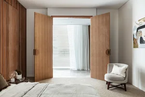 A modern bedroom featuring wooden paneling, blinds, curtains, and a textured floor.