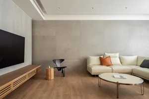 Minimalist living room with a concrete wall and a large, white sectional sofa.