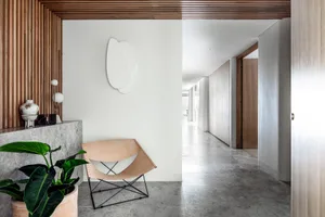 Modern, minimalist leather chair on concrete floor with a geometric ceiling design.