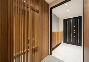 Modern entrance hallway featuring wooden walls and a black door.