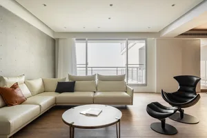 Modern minimalist living room with a white sofa, black chairs, and a round coffee table.