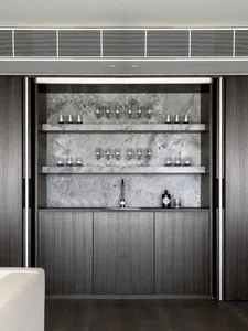 Modern bar area featuring marble countertops and shelves with glasses.