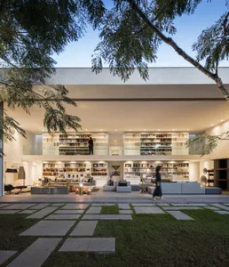 A modern, minimalist residential interior with an outdoor patio featuring concrete flooring and a garden.