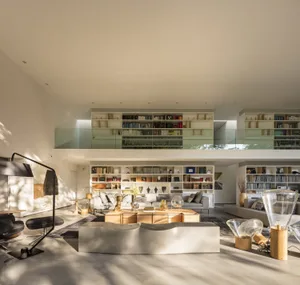 A minimalist living room with a concrete and wood coffee table, glass lamp, and wood sofa.