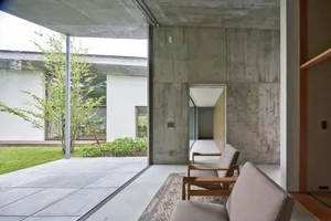 A minimalist living space featuring concrete walls and furniture in a modern, open-concept design.