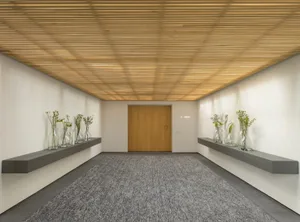 Minimalist lobby with concrete walls, wood ceiling, and glass vases.