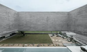 A modern outdoor space with concrete walls, a grassy area, and a small garden.