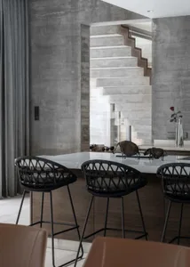 A modern kitchen with a concrete countertop and industrial-style seating.