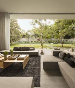 Modern living room with grey sofas, black rug, and plant.