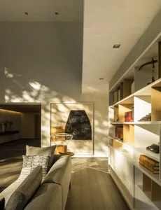 A modern living room featuring wooden flooring, glass artwork, and metallic shelving.