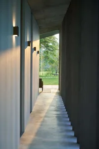 A minimalist concrete hallway leading to a garden.