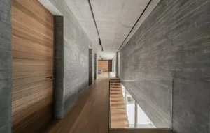 A minimalist concrete interior with wooden accents and a glass railing.