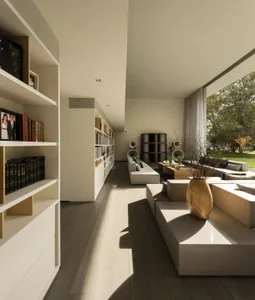 A modern minimalist living room featuring a combination of white and wooden furniture, large windows, and a spacious open flo