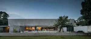 A modern residential house with a minimalist design, featuring a concrete exterior and a large pool in the yard.