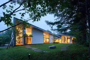 Modern residential exterior with large glass windows and a well-maintained lawn.